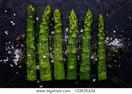 Asparagus With Sea Salt And Olive Oil On Black Stone Plate Top View