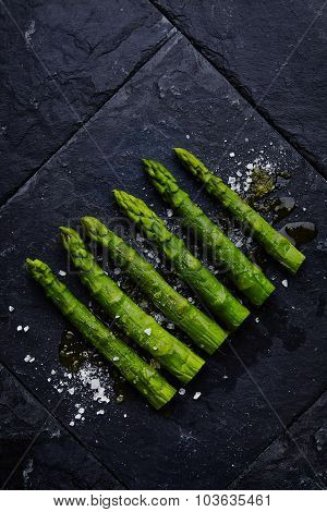 Asparagus With Sea Salt And Olive Oil On Black Stone Plate Top View