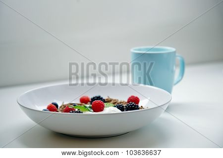 Musli For Breakfast With Mix Of Berries And Mint Leaves On Table With Blue Cup
