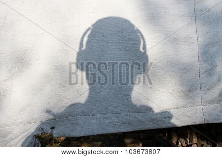 The Shadow Of A Man's Head With Headphones On Old Canvas Tarps
