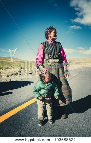 A Tibetan farmer with her kid in a steppe in Tibet, China