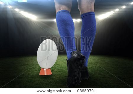 Low section of rugby player about to kick the ball against rugby stadium