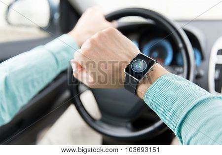 transport, business trip, technology, time and people concept - close up of man with engine start button on smart watch driving car