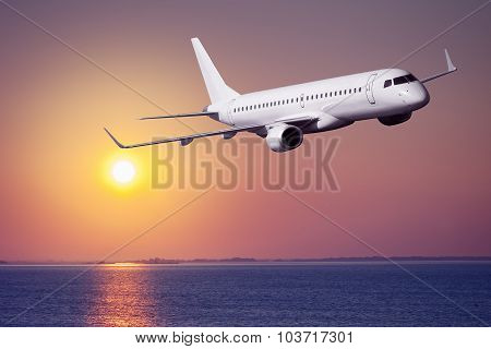Passenger airplane flying on sunset