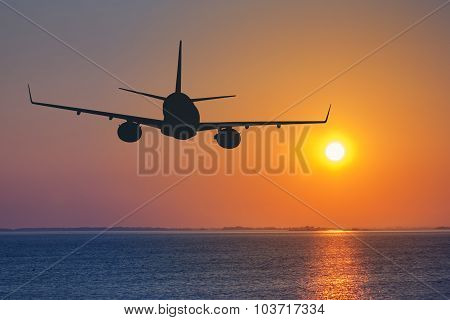 Silhouette Of Passenger Airplane Flying On Sunset