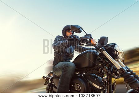 A young man riding a chopper on a road in blur motion