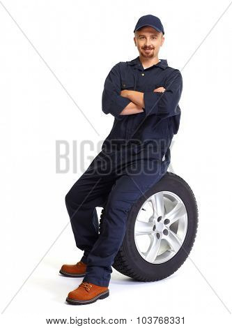 Smiling car mechanic with a tire isolated on white background.