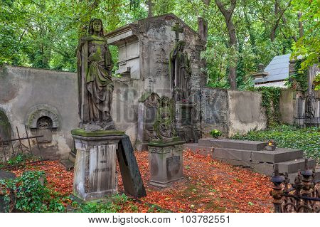 PRAGUE, CZECH REPUBLIC - SEPTEMBER 23, 2015: Statues and graves on old Olsany Cemeteries - largest graveyard in Prague with 2 million burials, created in 1680, noted for its remarkable monuments.