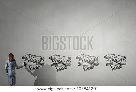 Back view of businesswoman drawing money banknotes on wall