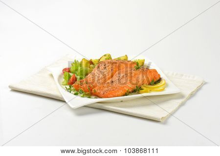 pan fried salmon fillets served with vegetable garnish on white plate and place mat