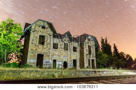 Abandoned train station with star trails at night