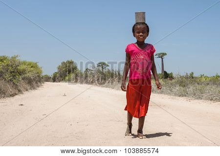 MORONDAVA, MADAGASCAR - DECEMBER 08 Portrait of unidentified girl carries can on her head, December 08, 2013, Morondava region, Madagascar. Children in Madagascar are friendly and often barefoot.