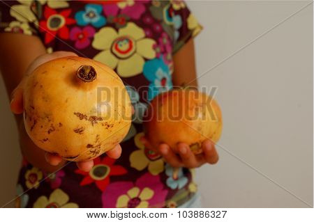 Young girl offering ripe pomegranate fruit, clear concept for giving natural and healthy food.