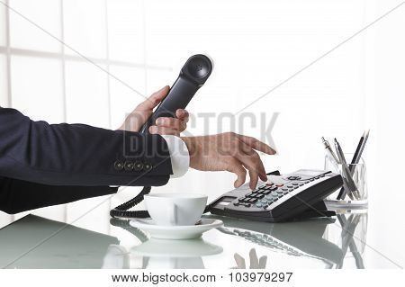 Businessman Hands Dialing Out On A Black Deskphone