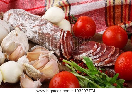 Salami With Cherry Tomatoes, Ruccola And Garlic On A Cutting Board