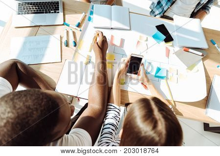 Involved in group work. Top view of smart students sitting at the table and working on the project while getting ready for classes