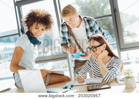 Online studying. Cheerful young group of students using their laptop and making notes while studying together