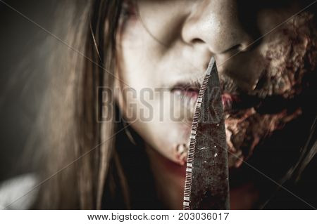 Asian girl dress killer to Halloween festival She's holding a kitchen knife and a big soaked with blood with terrible eyes ready to kill people.