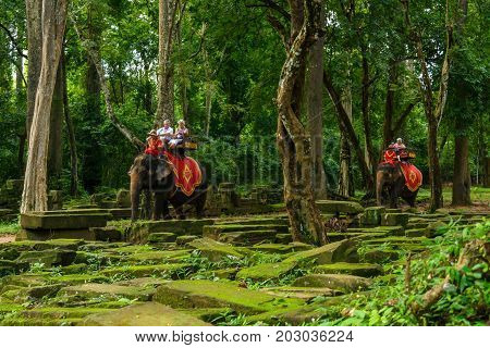SIEM REAP CAMBODIA - SEPTEMBER 1 2015: Tourists ride elephants around the Bayon temple at the Angkor Wat complex.