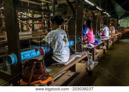 SIEM REAP CAMBODIA - AUGUST 24 2015: Women weave decorative cloths with silks at a silk farm.