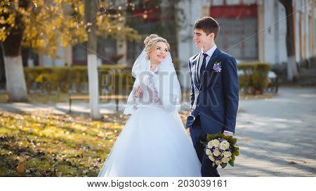 Happy bride and groom walking in the park.