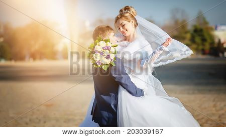 The bride and groom laugh and look at each other with love in the sun.