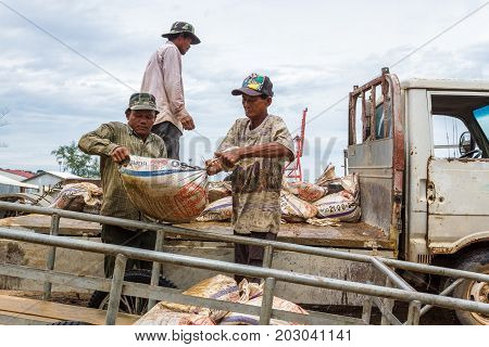 SIHANOUKVILLE CAMBODIA - 7/20/2015: Cambodian laborers offload bags of Ammonium Sulphate Fertilizer in a small fishing village.