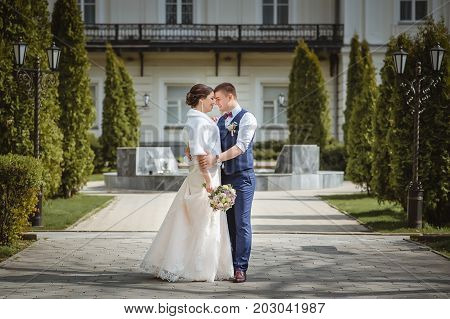 The bride and groom are hugging in the city park for a walk.