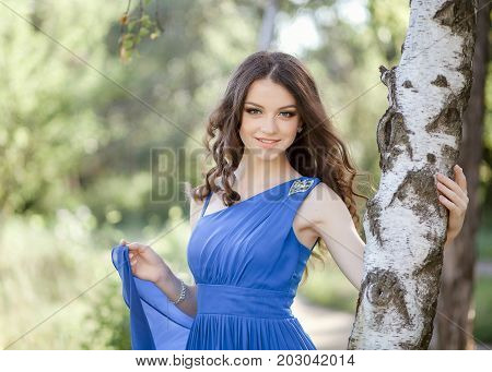 An innocent young smiling brown-haired woman in the forest.