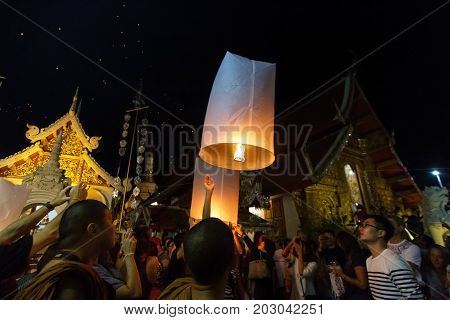CHIANG MAI THAILAND - 12/30/2015: A group releases floating lanterns at a Buddhist temple on New Year's Eve in Chiang Mai Thailand.