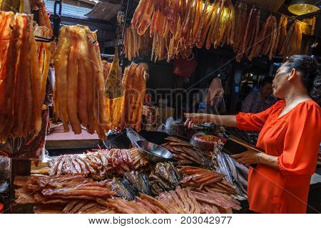 PHNOM PENH CAMBODIA - AUGUST 11 2015: A customer speaks with a meat vendor in the Russian market in Phnom Penh.