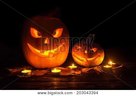 Two pumpkin jack-o-lantern with smiles carved on Halloween with a candle backlight