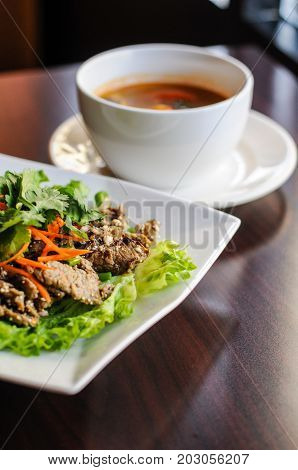 Nam Tok Spicy Beef Salad, Char-broiled tender slices of beef mixed with red onion, green onions, roasted rice, cilantro, chili powder & citrus leaves