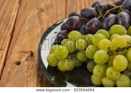 Fresh tasty grape with branch on wooden background