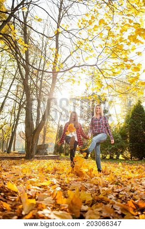 Funday with mom. Soft focus full length portrait of a beautiful woman having fun with her daughter walking in an autumn park