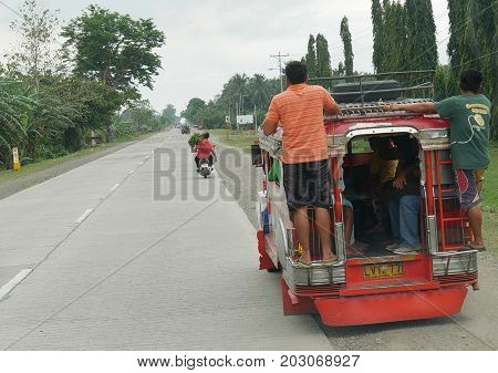 DAVAO  DEL NORTE, PHILIPPINES--A jeepney, the most pupular transportation with two people riding outside, a common practice in the Philippines. . Taken in March 2016 in Pantucan, Davao del Norte.
