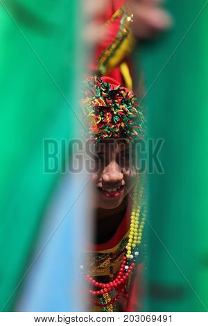 DAVAO CITY, PHILIPPINES--AUGUST 2014: A girl peeks out through bamboo poles at the parade grounds. Kadayawan is celebrated August each year to give thanks for life and an abundant harvest.