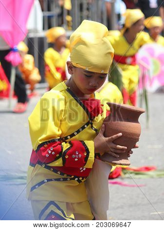 DAVAO CITY, PHILIPPINES--AUGUST 2014: A girl joins the streetdancing competition with an earthen jar at the parade. Kadayawan is celebrated August each year to give thanks for an abundant harvest.