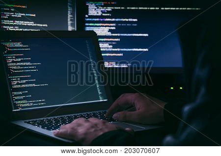 Hacker working on a code in dark room. Programming code on screen. Internet crime concept