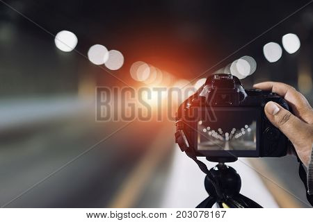 Man holding camera press shutter on tripod on subway tunnel with light bokeh