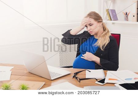 Tired pregnant businesswoman at office copy space. Expectant business lady feeling sick at work, gestosis concept