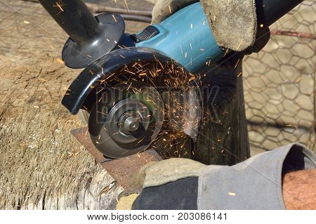 Electric grinder. A man working with electric grinder tool on steel structure sparks flying