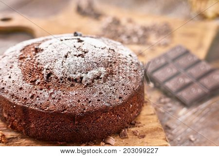 Delicious chocolate cake in white plate on wooden table background, closeup