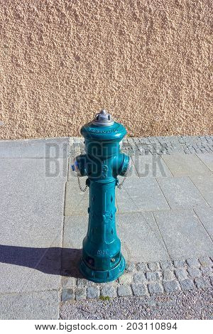 The green old fireplug against a stone wall background at Salzburg, Austria