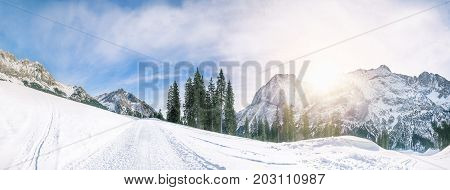 Stunning winter panorama with the peaks of the Austrian Alps mountains the evergreen fir forests and an alpine road all covered in snow in Ehrwald Austria.