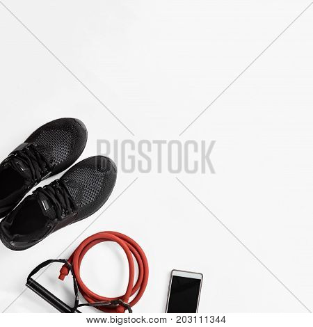 Athlete's male set with mobile phone, elastic expander and gymshoes, image with Square ratio