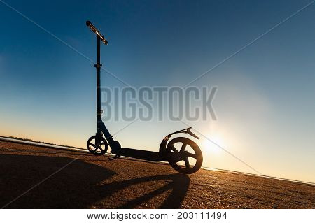 Kick scooter on asphalt running track , under sunlight at sunny summer day. Wide angle image.