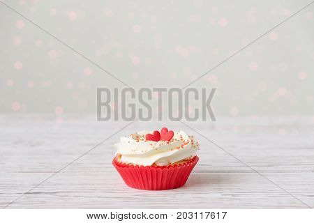 Cupcake with heart decoration on white wooden background. Love and Valentine's day concept or Sweetest day. Space for design