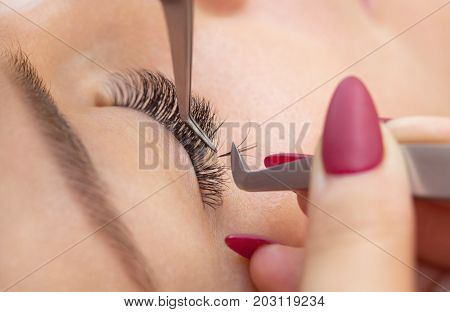 Eyelash removal procedure close up. Beautiful Woman with long lashes in a beauty salon. Eyelash extension.