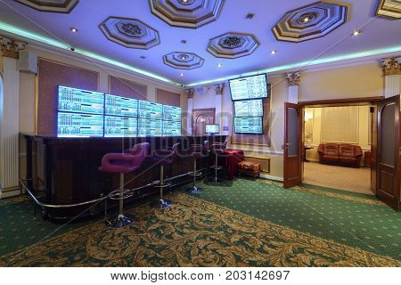 Empty wooden counter and lot of screens in luxury bookmaker office with carpet, my photo in frame